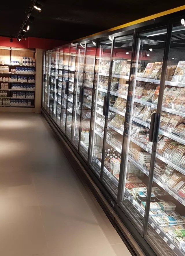 Allée de meubles frigorifiques fermés par des portes vitrées