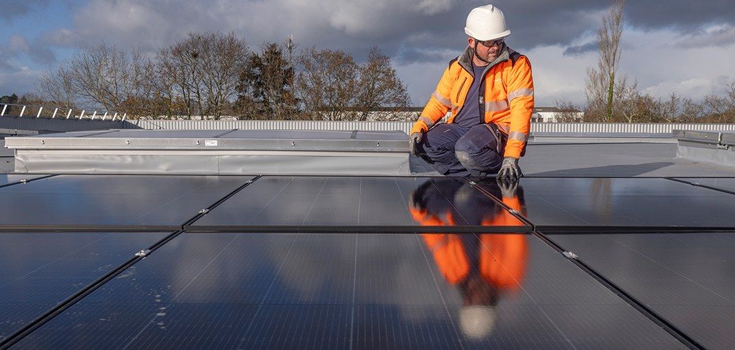 Technicien sur une toiture équipée de panneaux photovoltaïques